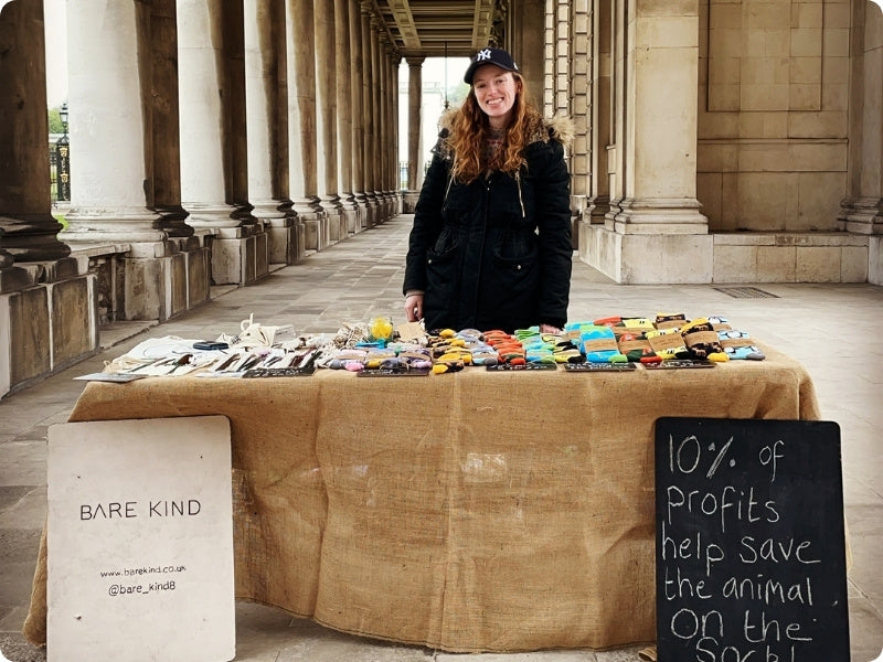 Lucy standing behind a table with Bare Kind products in an outdoor setting