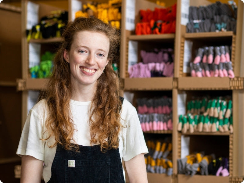 Lucy standing in front of shelves filled with various socks in a store setting