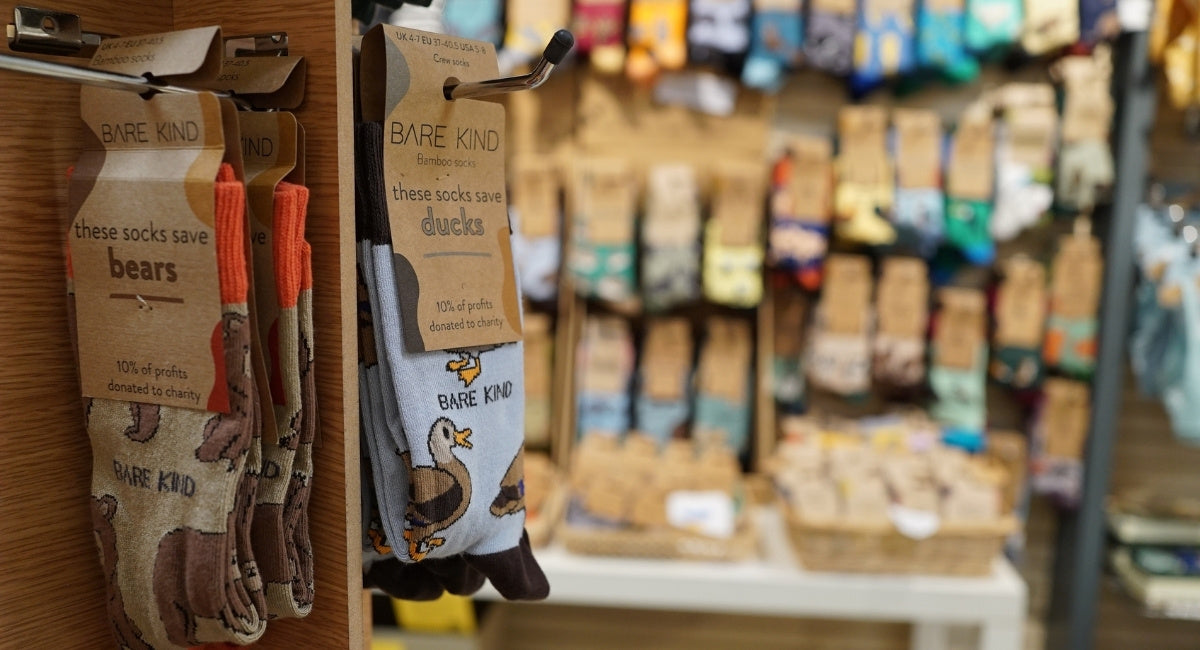Bare Kind socks displayed on a rack with a store setting in the background